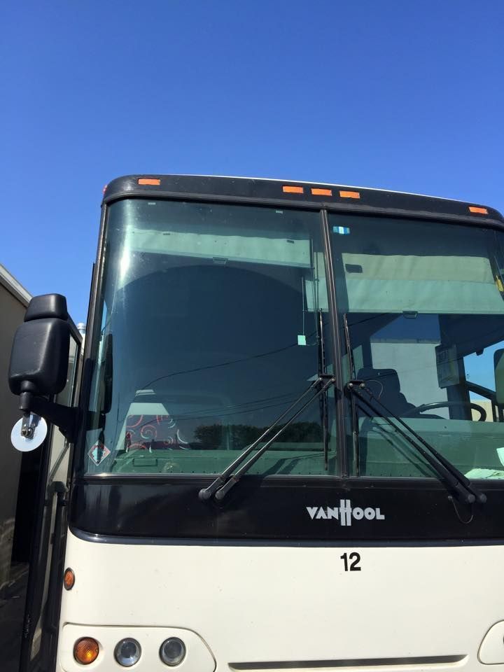 Front view of a black and white Van Hool bus against a clear blue sky