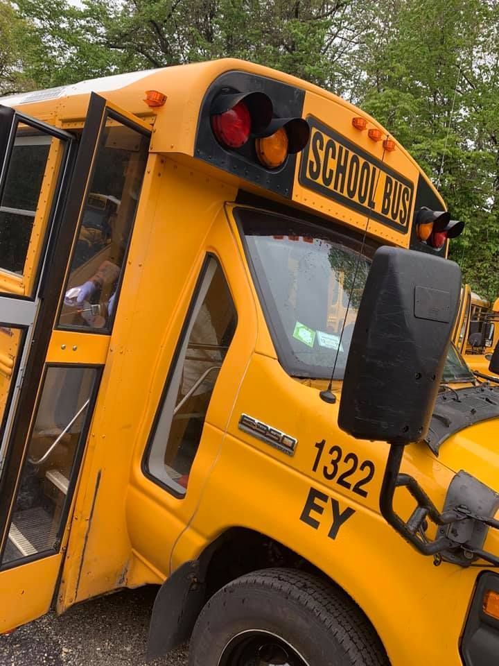 Yellow school bus parked at an angle, with open door and black “SCHOOL BUS” sign visible.
