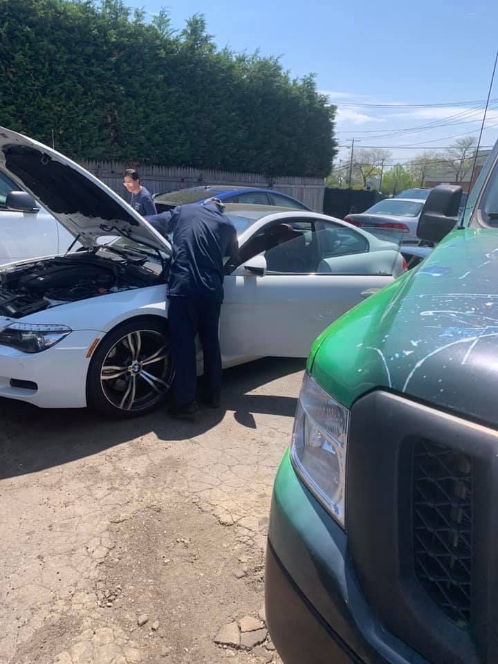 Two cars with hoods open after a roadside incident, with a person inspecting the white car.