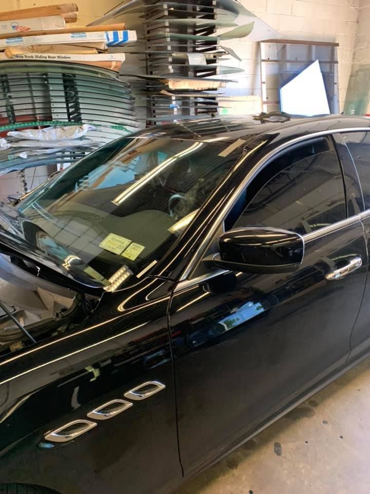 Black sedan parked in a garage, with skis stacked on wall racks beside it.