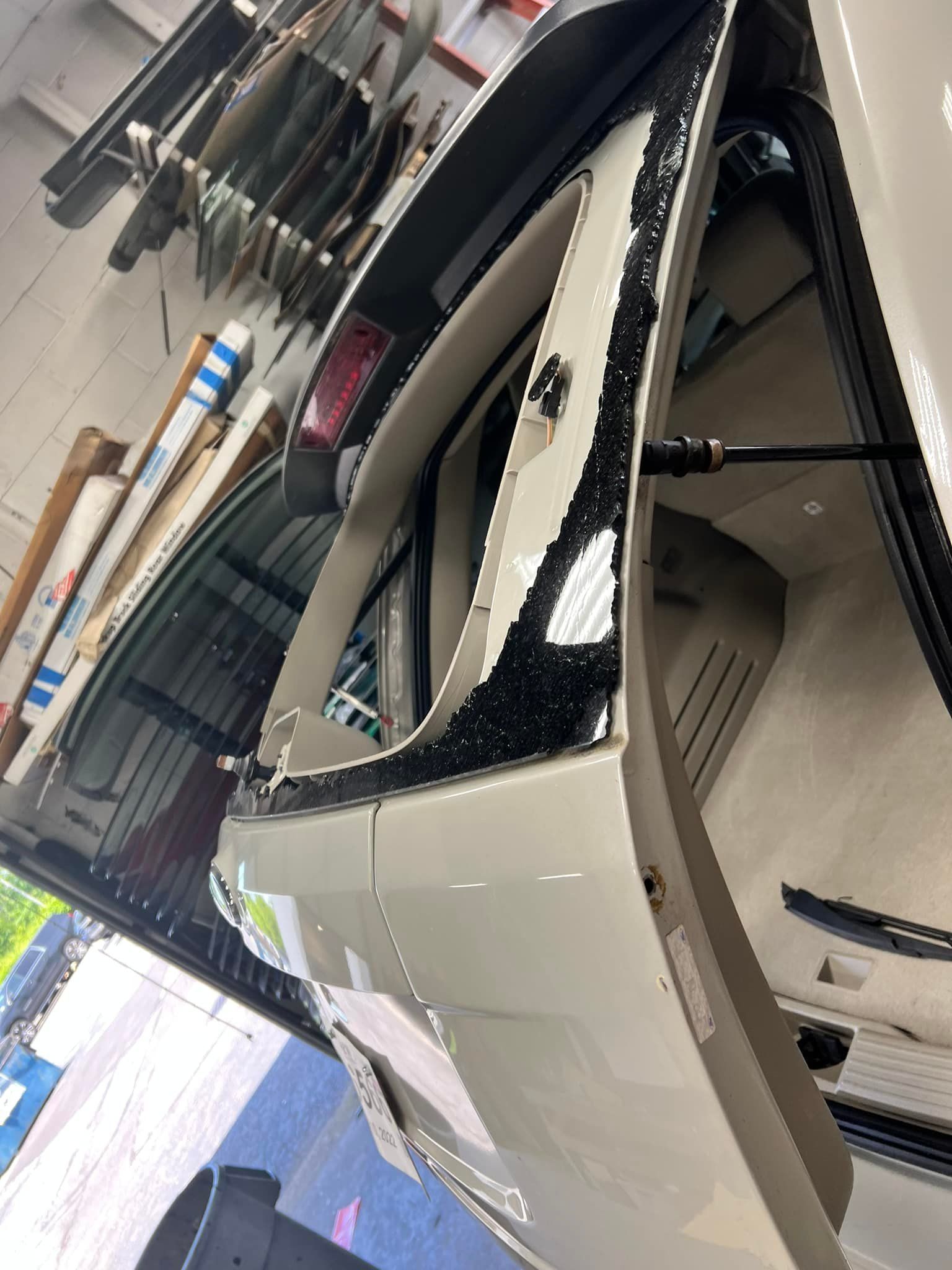 White car body shell in a workshop, with hanging tools and parts visible nearby.