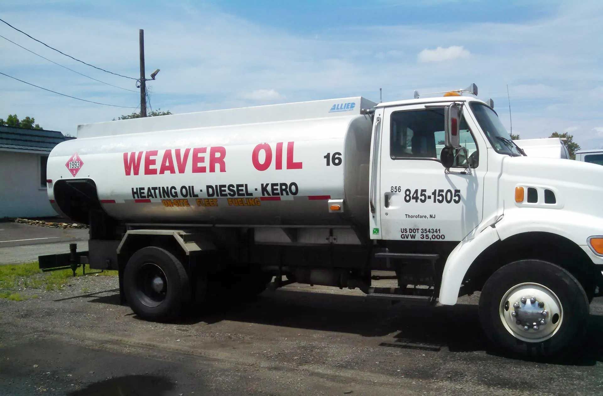 White Weaver Oil truck parked, with red and yellow text and a hazardous materials diamond.