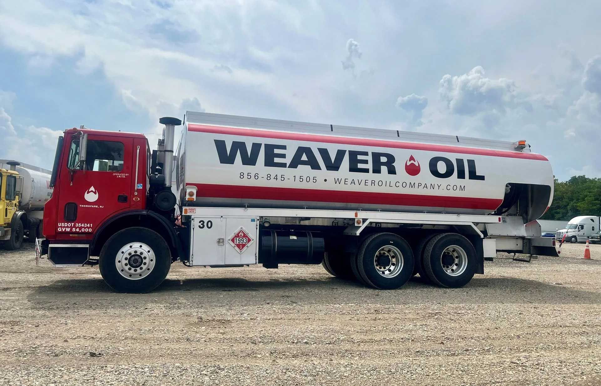 Red and white Weaver Oil tanker truck parked outdoors.