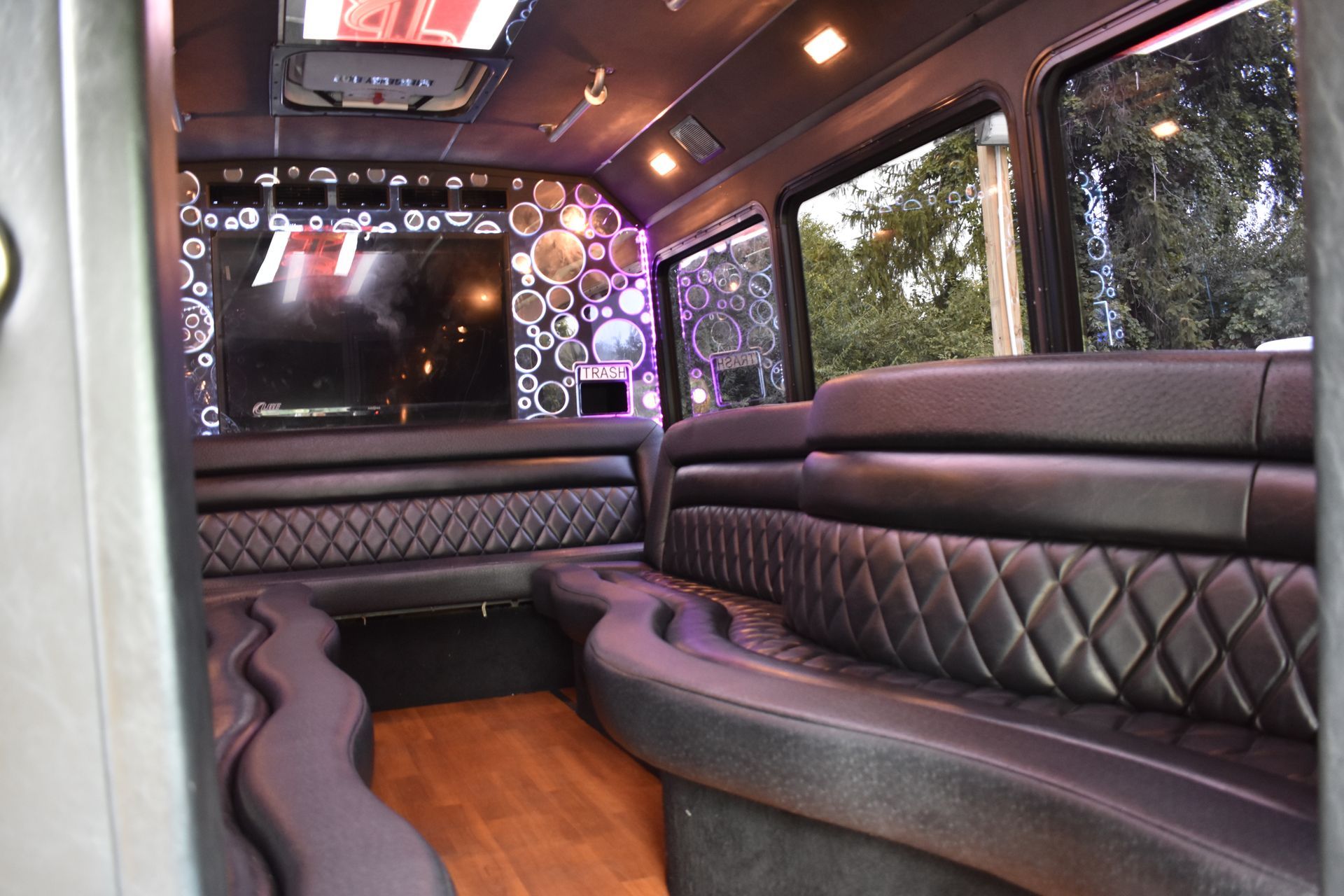 The inside of a shuttle bus with purple seats and a flat screen tv.