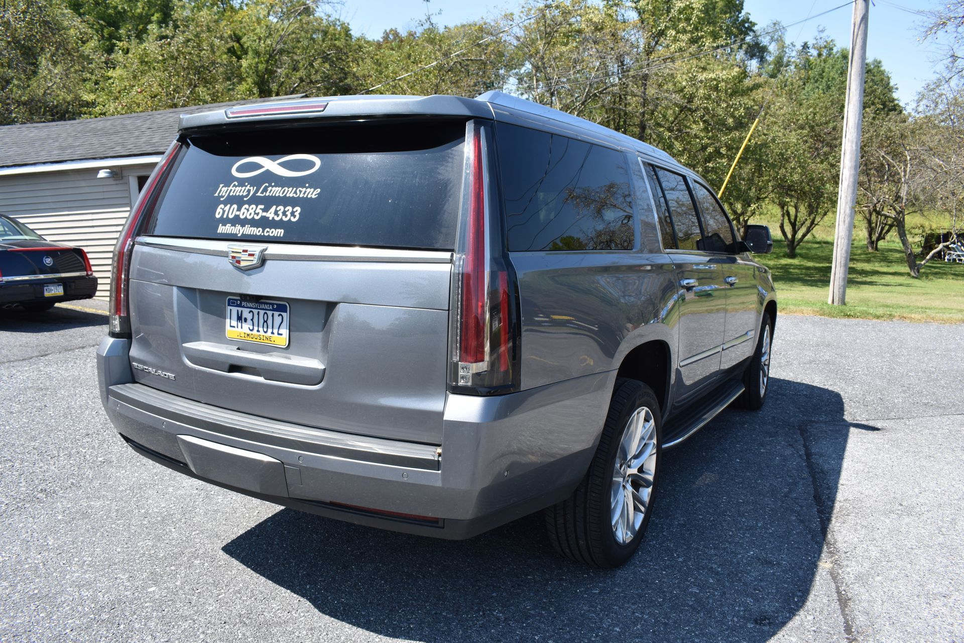A gray cadillac escalade is parked in a driveway.