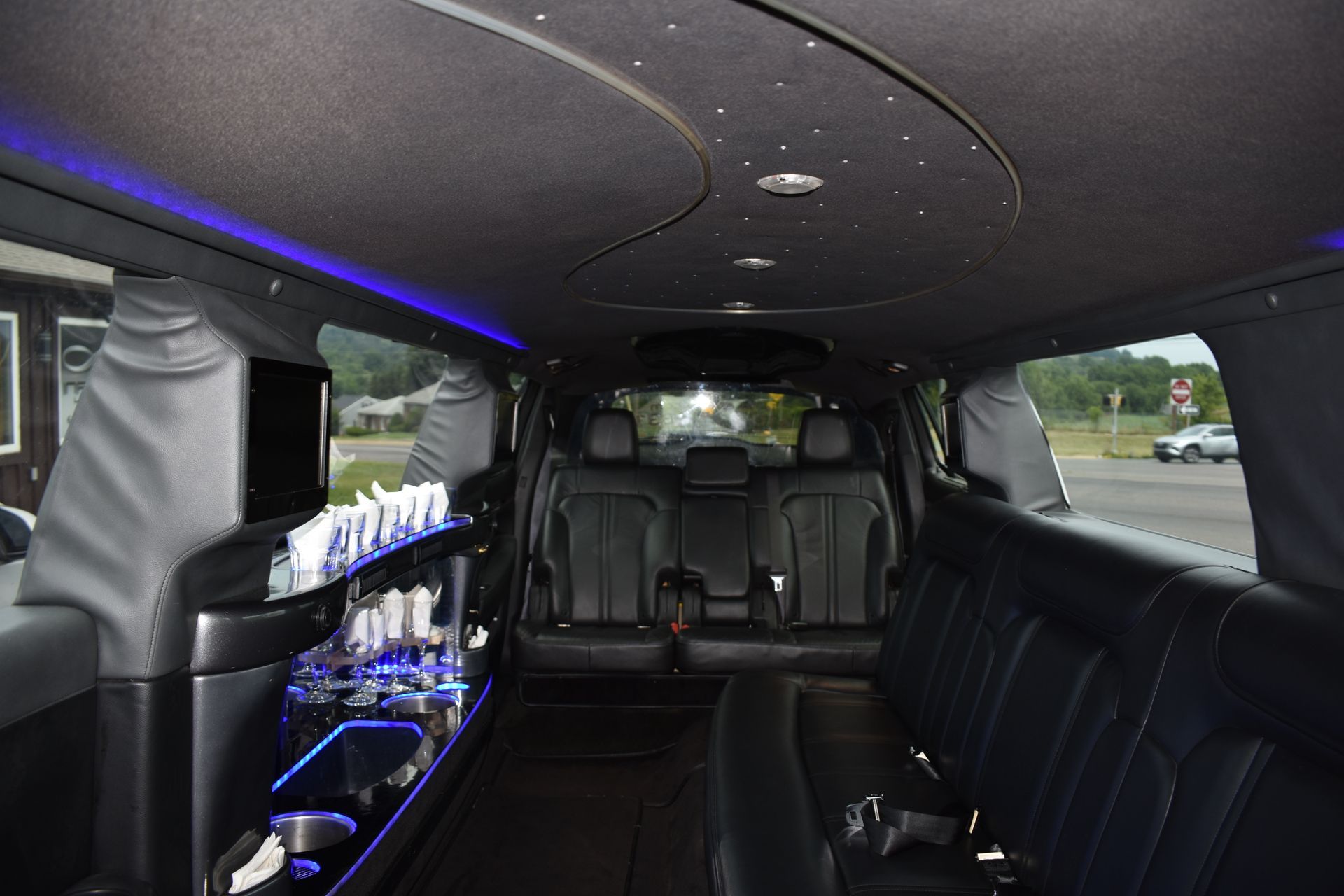 The inside of a black limousine with a blue light on the ceiling.