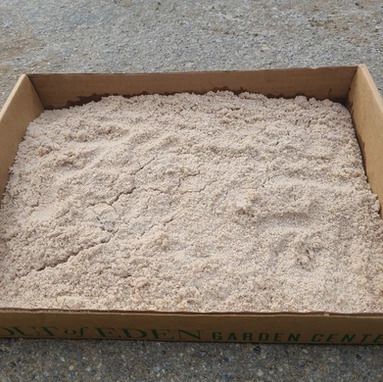 A cardboard box filled with sand is sitting on the ground