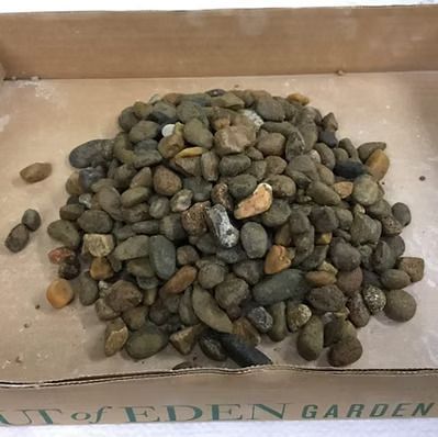 A pile of rocks in a box that says art of eden garden