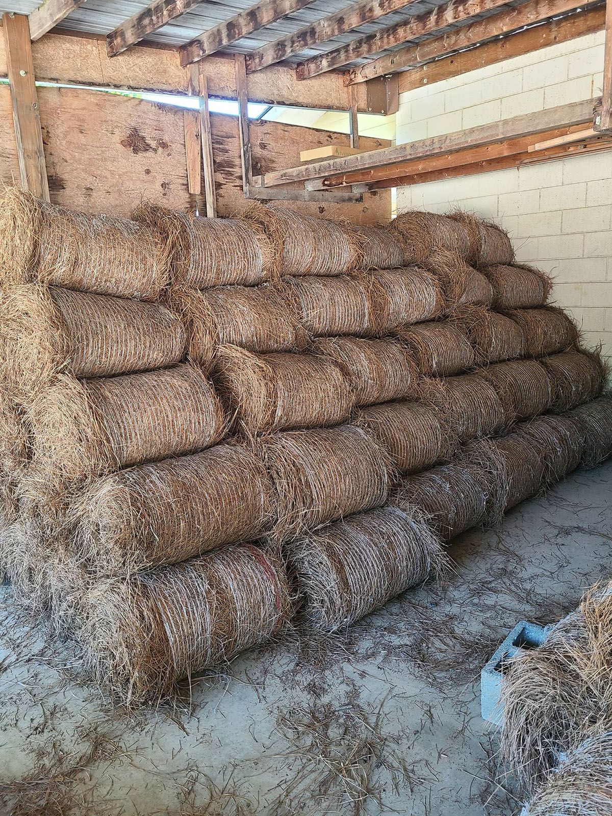 A bunch of hay bales are stacked on top of each other in a barn.