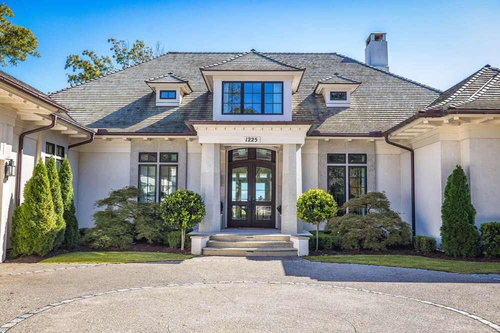 A large white house with a gray roof and a large driveway.