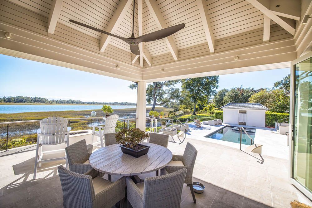There is a table and chairs on the patio with a ceiling fan.