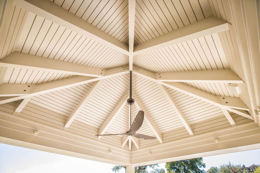 A ceiling fan is hanging from the ceiling of a gazebo.