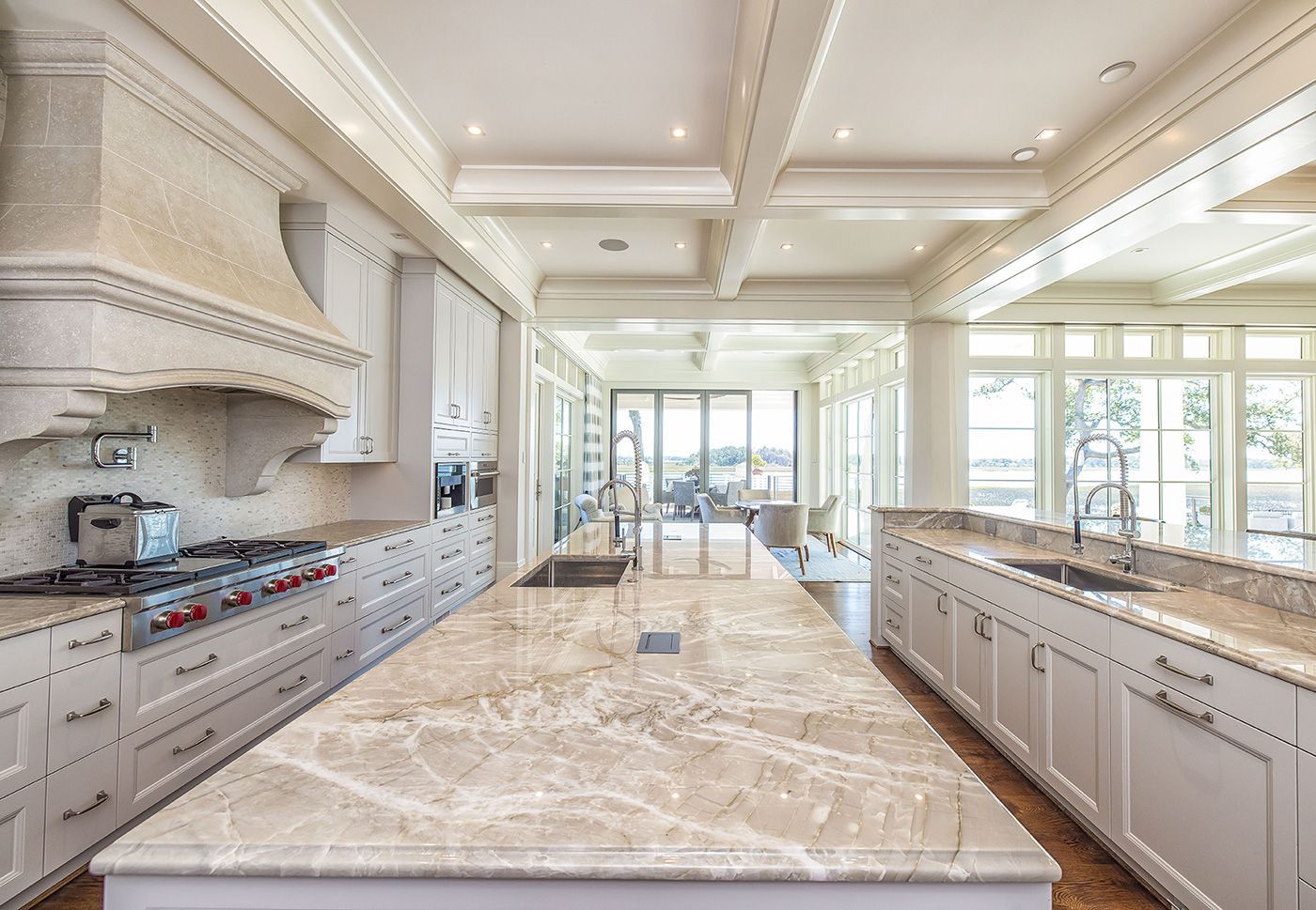 A kitchen with white cabinets, granite counter tops, and a large island.