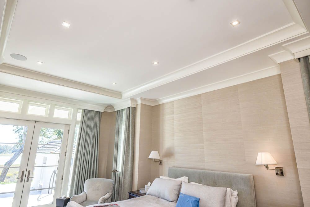 A bedroom with a bed, chair, and sliding glass doors.