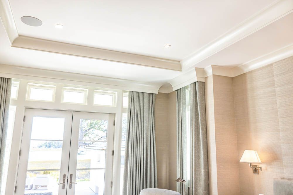 A bedroom with a bed, chair, lamp and sliding glass doors.