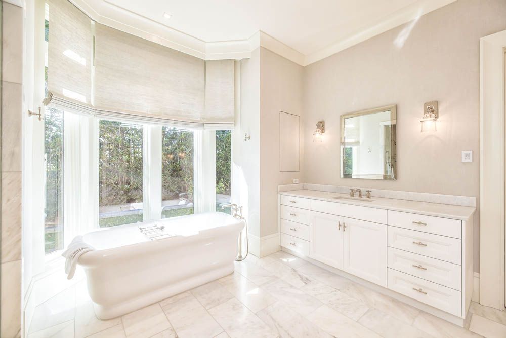 A bathroom with a tub, sink and mirror.