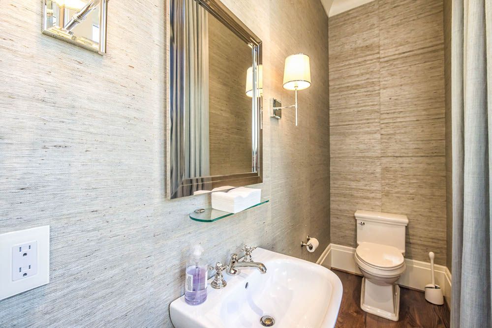 A bathroom with a sink, toilet and mirror.