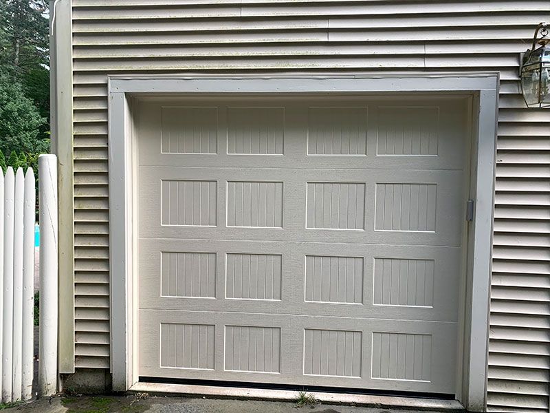 White garage door with rectangular panels on a house exterior