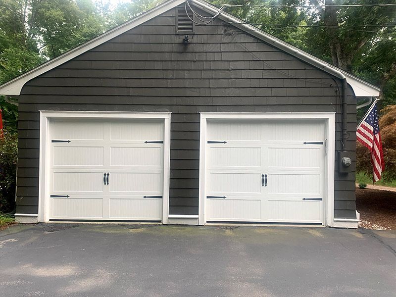 Gray two-car garage with white doors and an American flag on the right side.