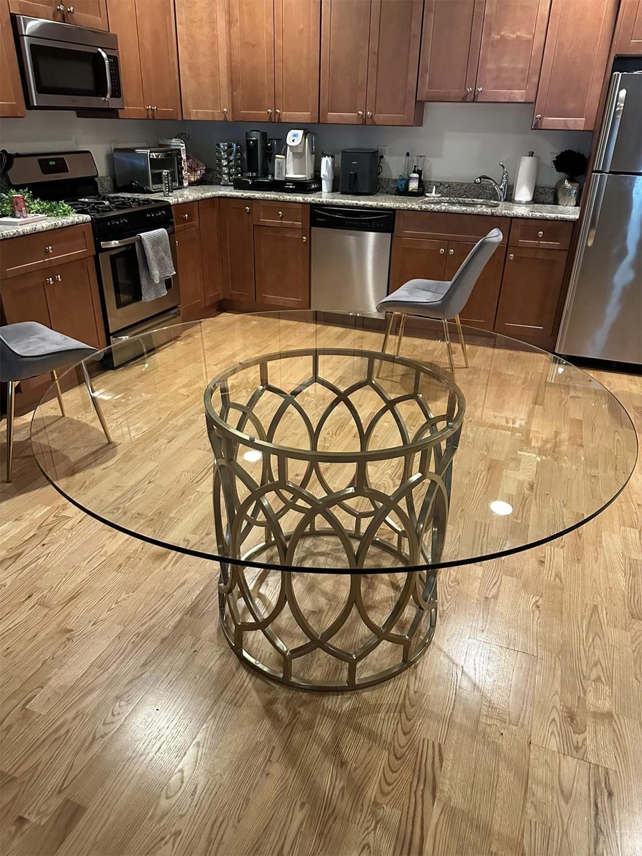 A kitchen with a round glass table and chairs.