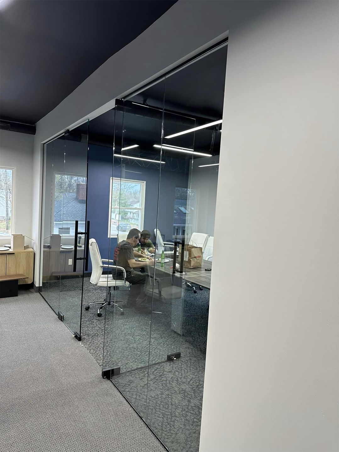 A conference room with a glass wall and sliding glass doors.