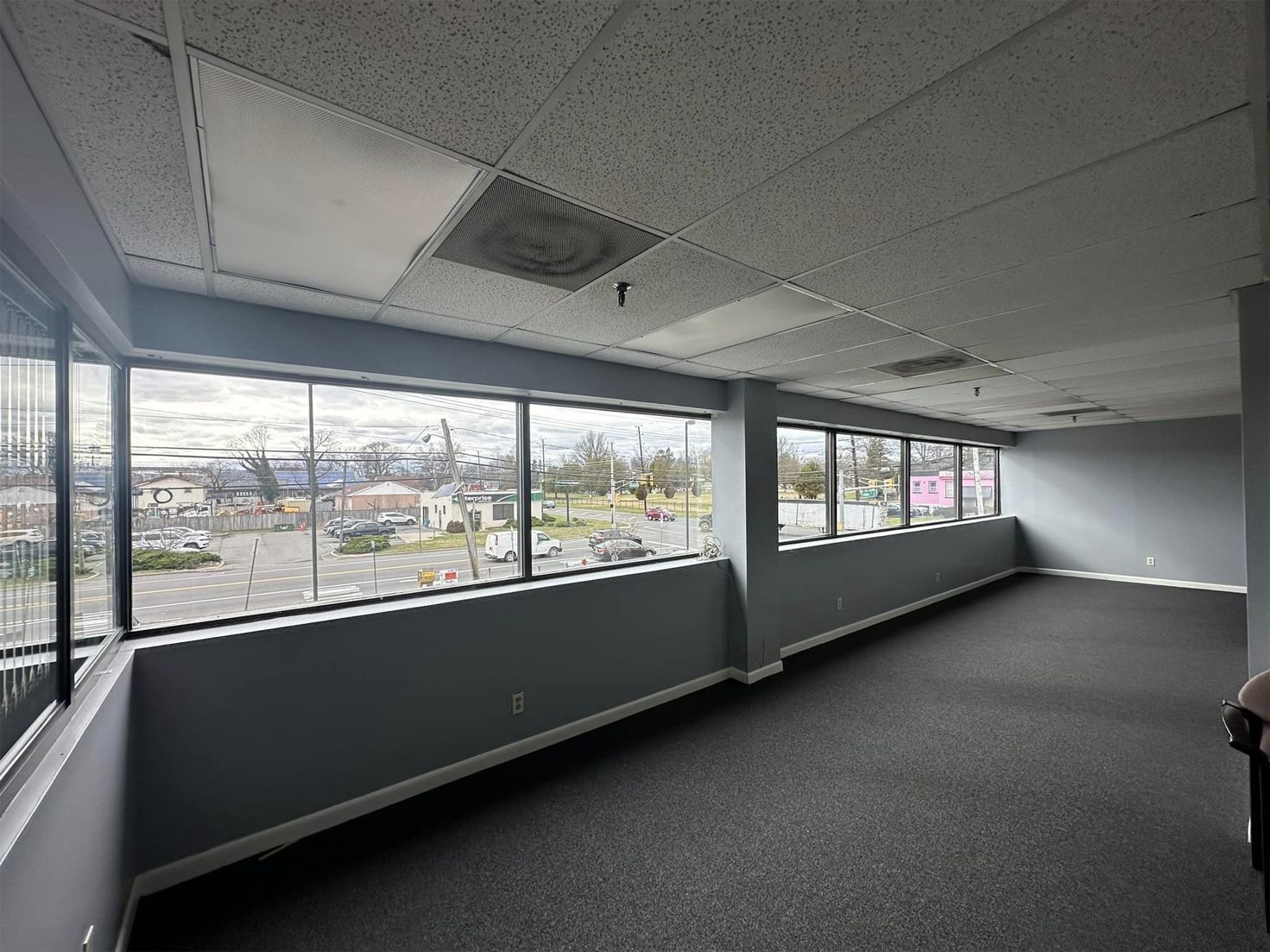 An empty room with a lot of windows and a view of a city.