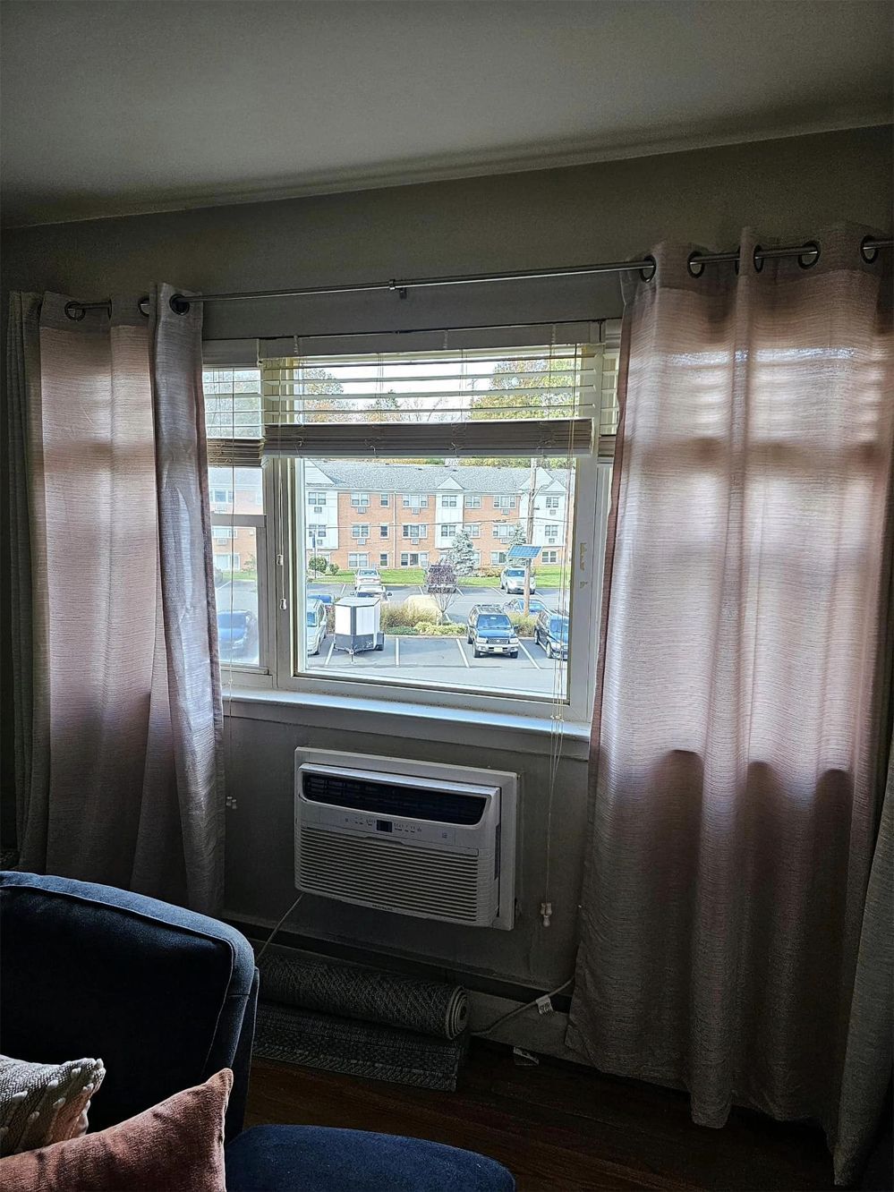 A living room with a window and a window air conditioner.