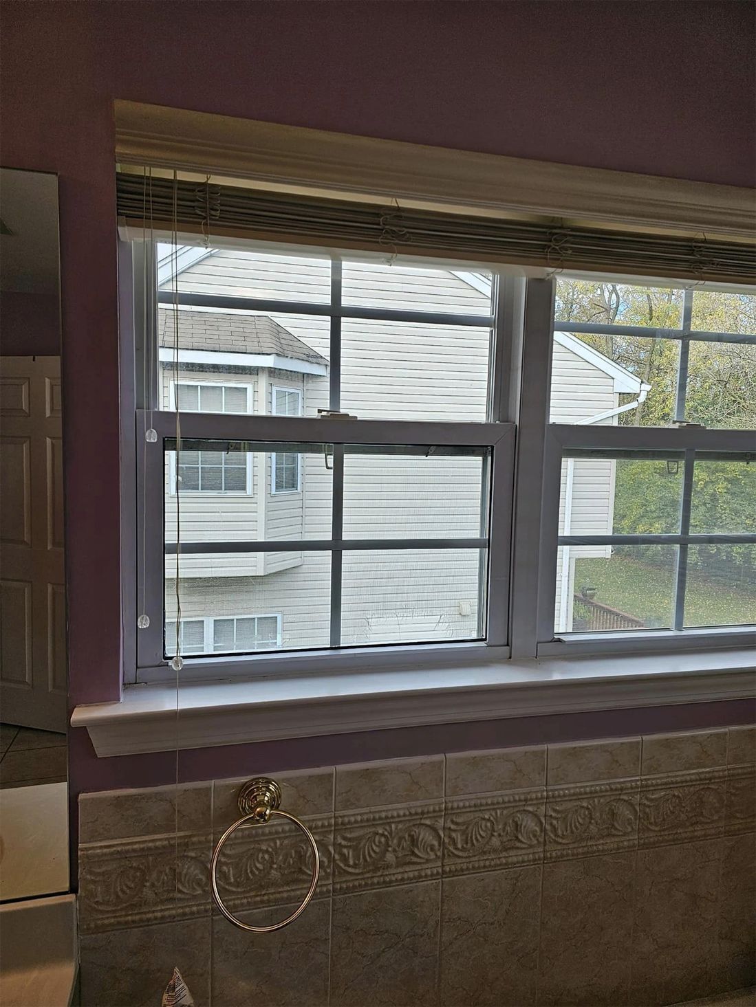 A bathroom with a window looking out to a house.
