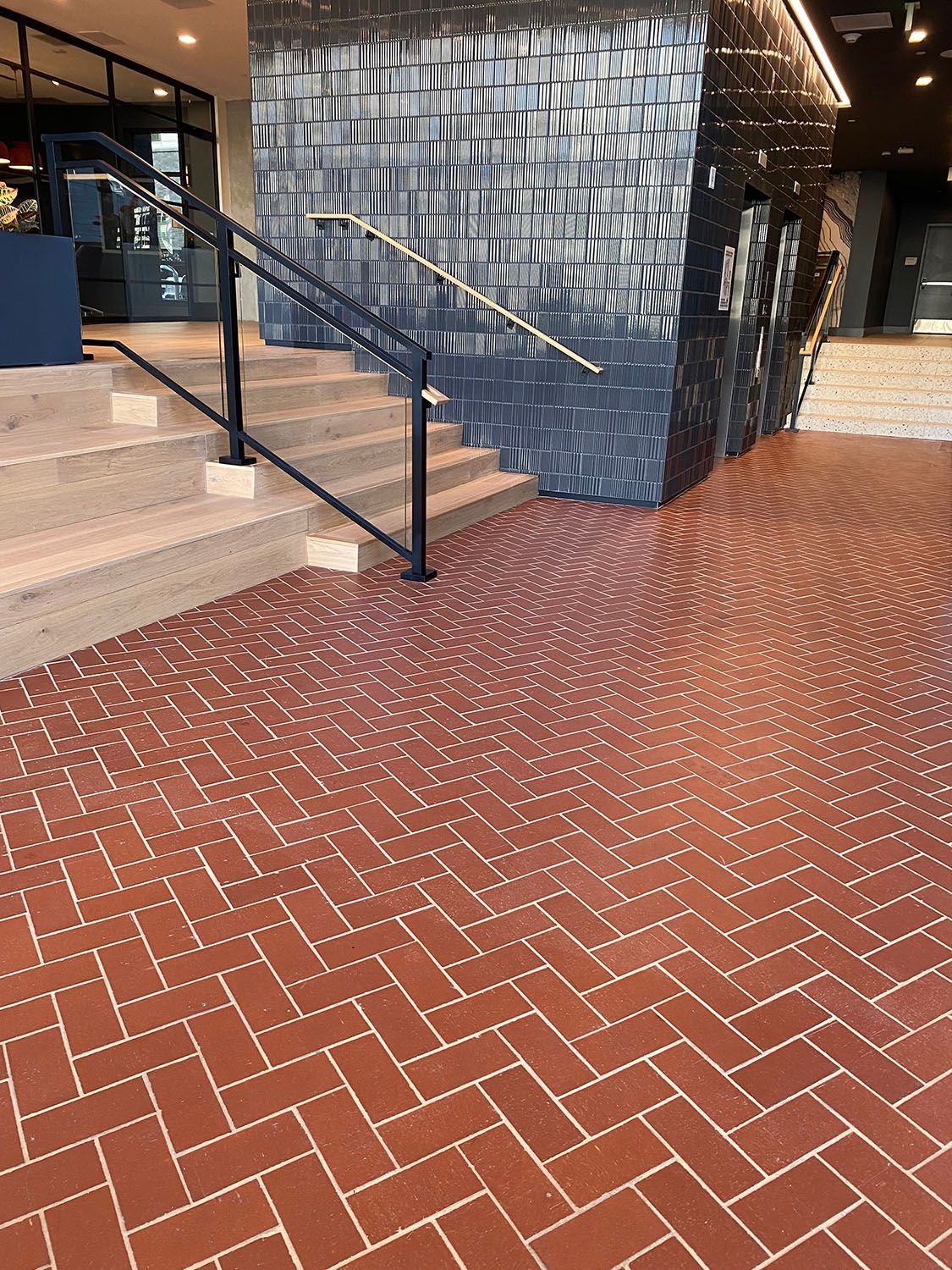 a brick floor with a herringbone pattern and stairs in the background