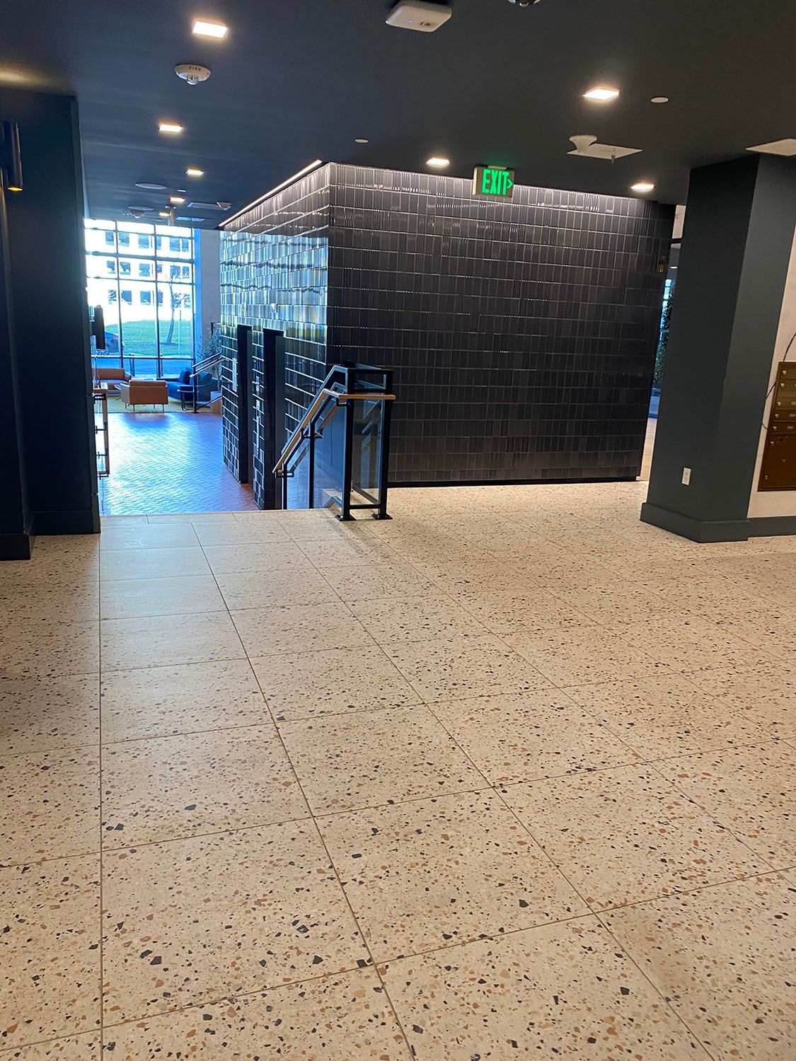 a large empty room with a terrazzo floor and stairs