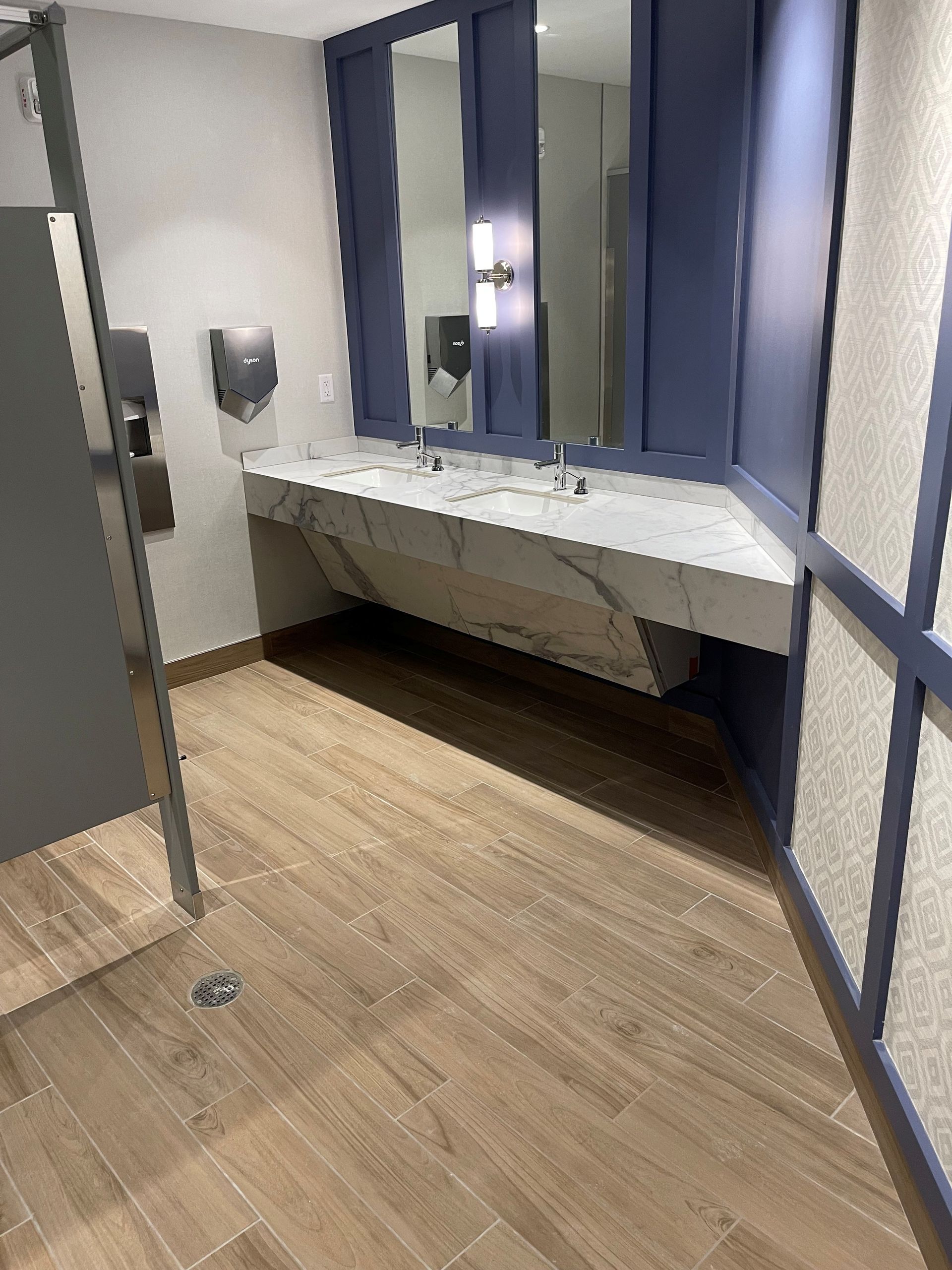 A bathroom with a sink , mirrors and a wooden floor