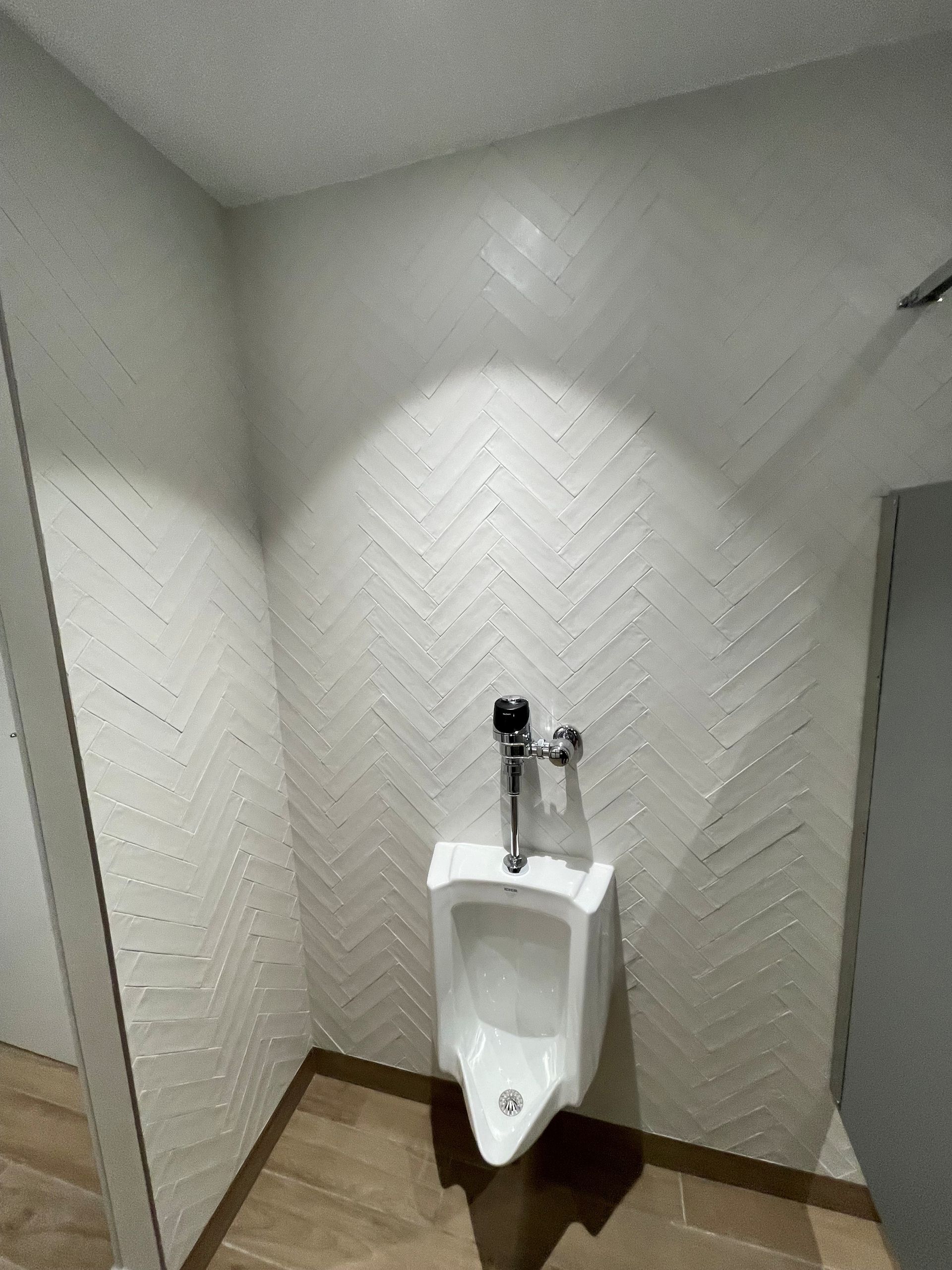 There is a urinal in the corner of a bathroom