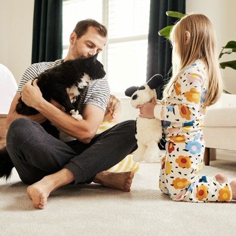 a man and a little girl are sitting on the floor playing with stuffed animals .