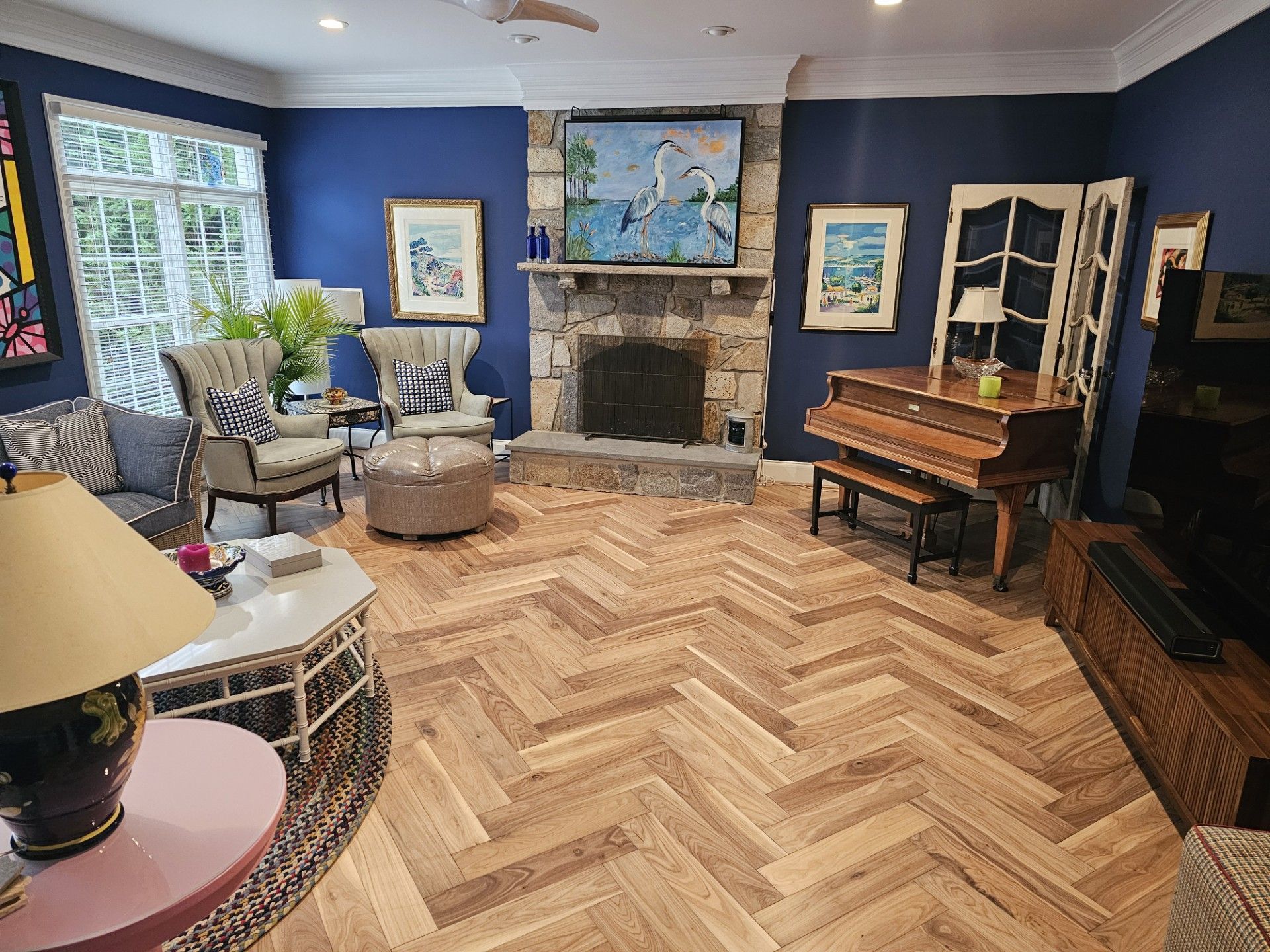 A living room with a piano, a fireplace and a nice hardwood flooring.