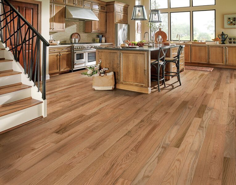 A kitchen with hardwood floors and stairs leading up to it.