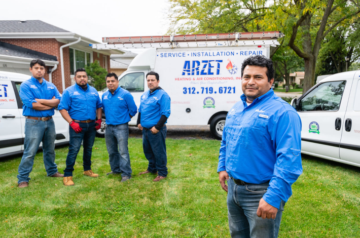 A group of men in blue shirts are standing in front of white vans