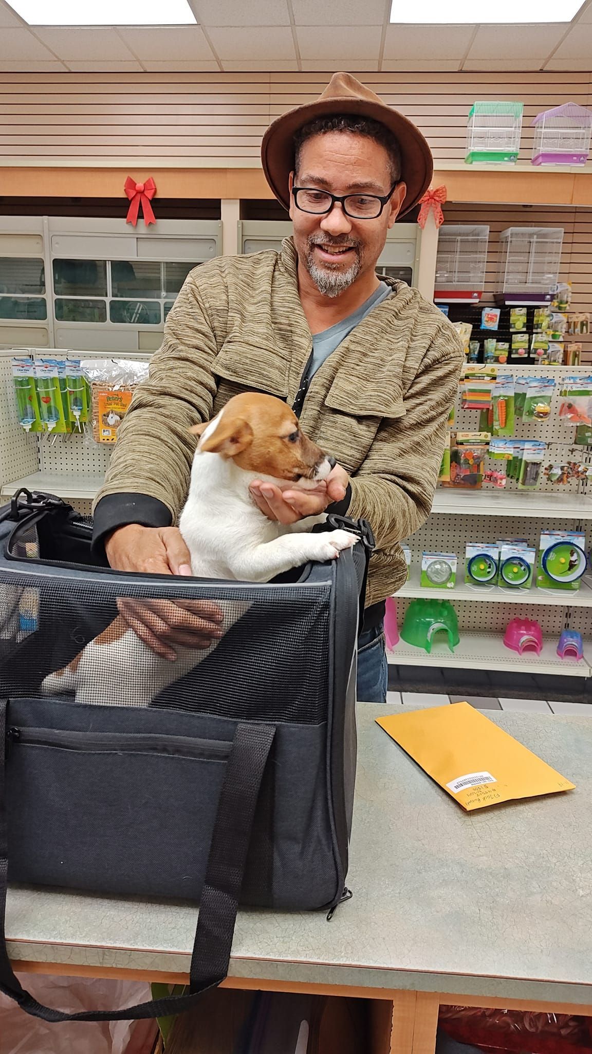 Person smiling while holding a small dog in a pet store checkout area