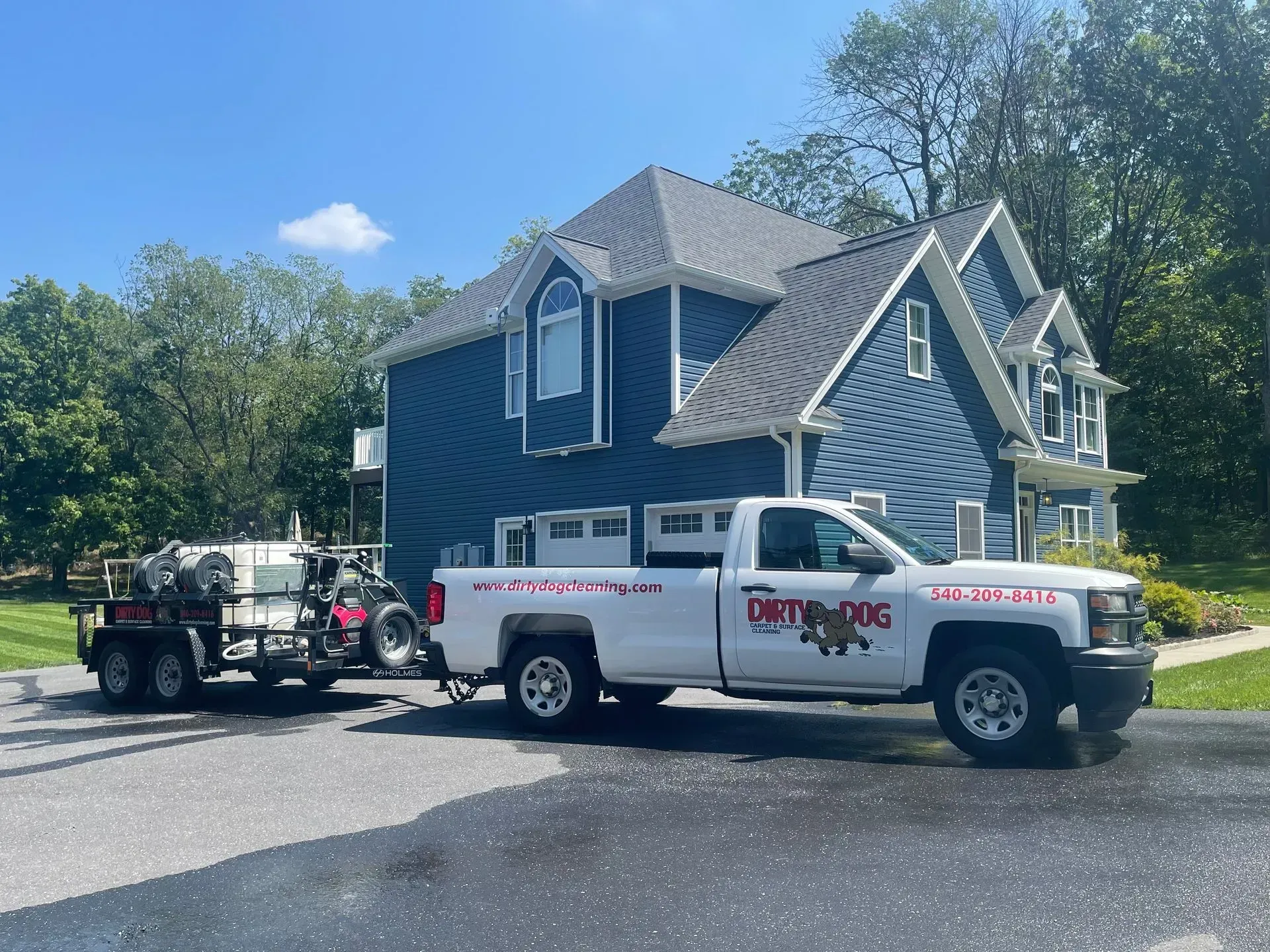 Blue house with two service trucks parked in front on a sunny day