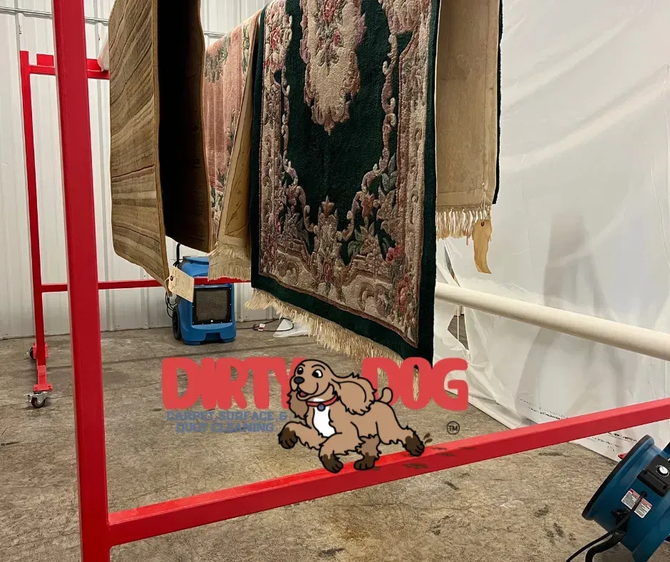 Red metal rack holding hanging rugs in a warehouse or storage area