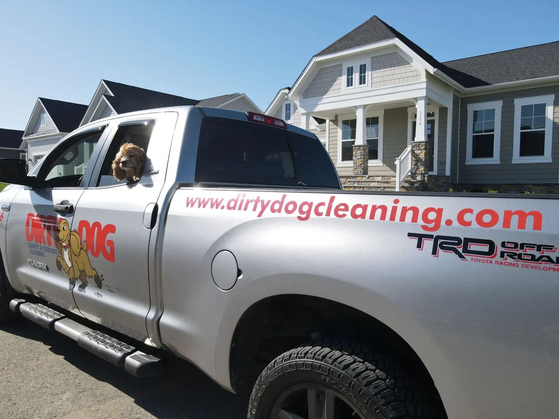 White service pickup truck for “dirtydogcleaning.com” parked in front of suburban houses.