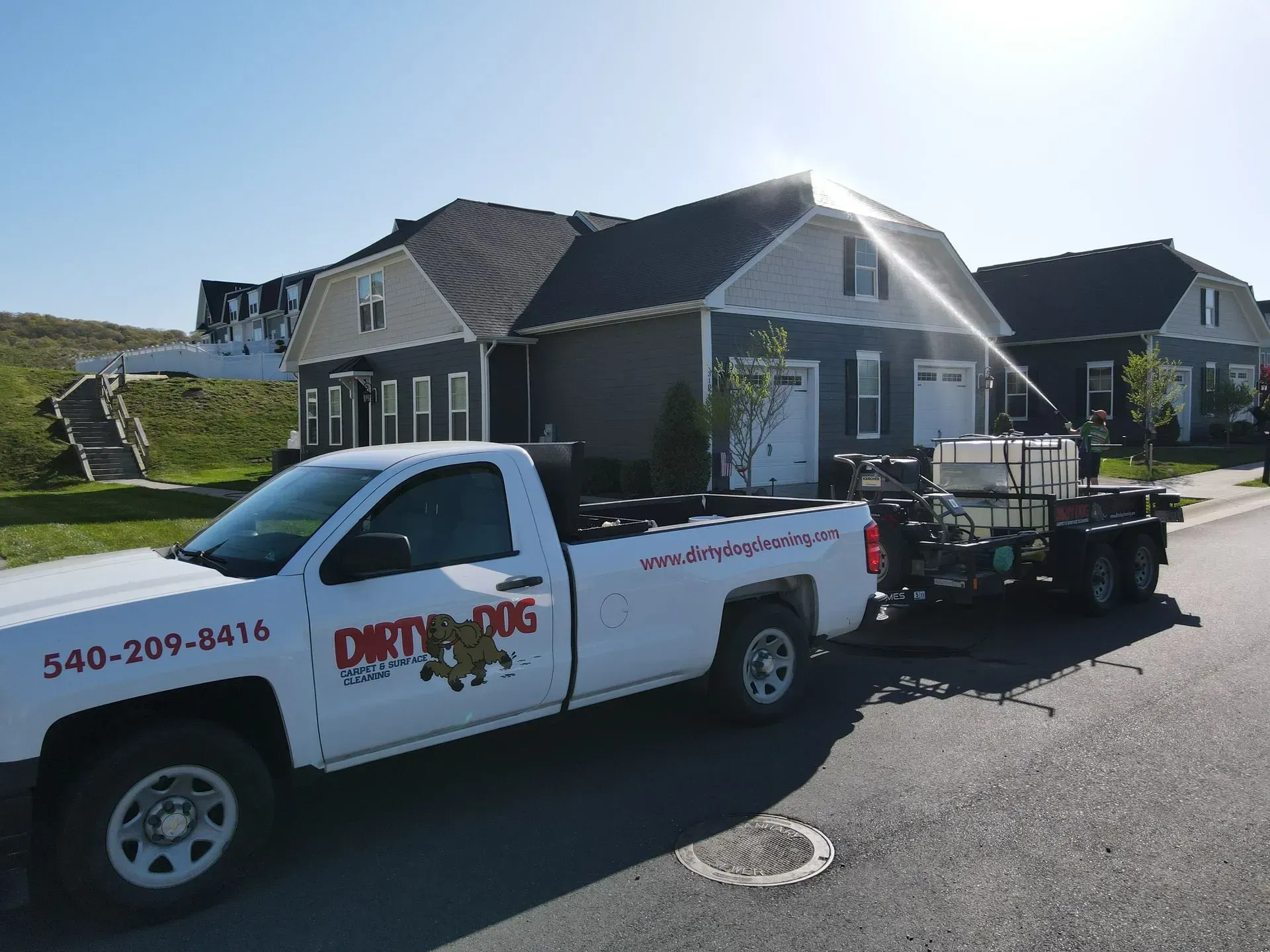 White work pickup truck hitched to a trailer parked on a sunny residential street in front of houses