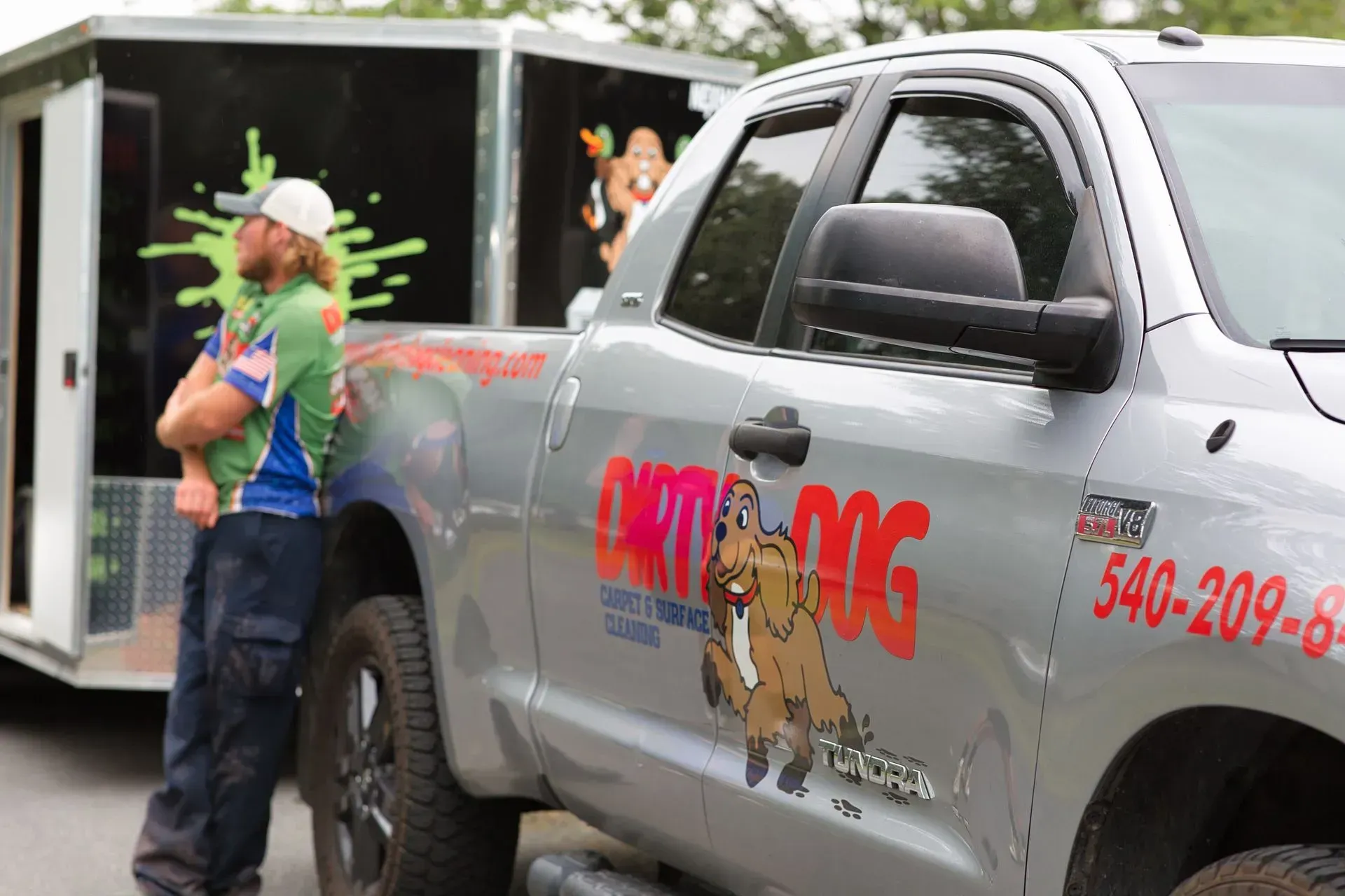 Man handing items to a gray pickup truck wrapped with “Bongo” logo and dog graphic at a storefront