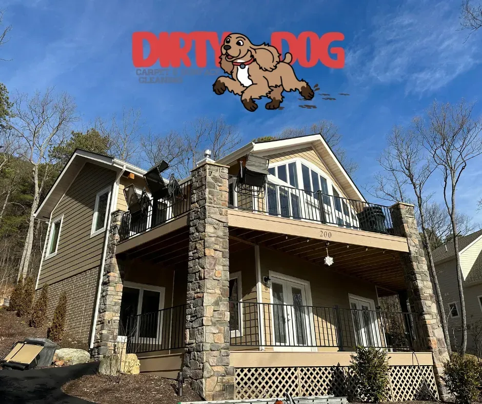Two-story house with balconies, stone pillars, and a red Dirty Dog logo against a blue sky