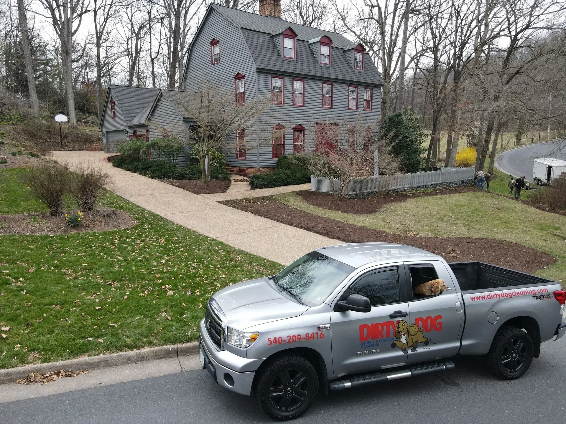 Silver truck parked in front of a gray house with red-trimmed windows and a curved driveway