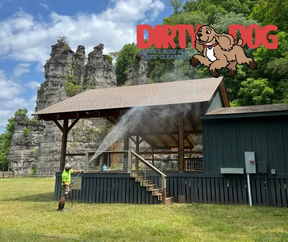 Outdoor stage with a misting spray, small building, and “Dirty Dog” sign against rocky cliffs and grass.