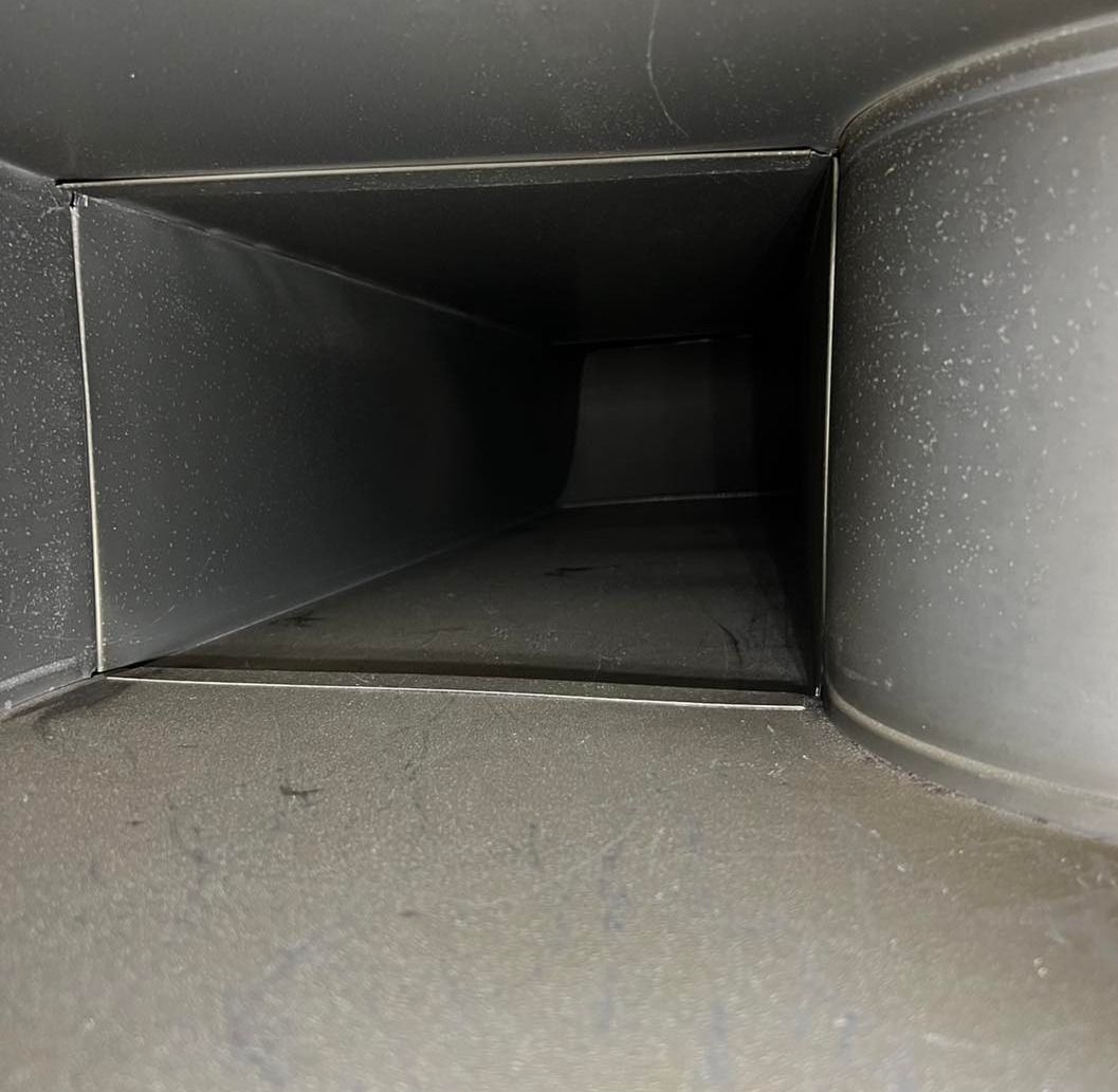 Inside of a metal duct, rectangular shape leading to a dark, distant end.