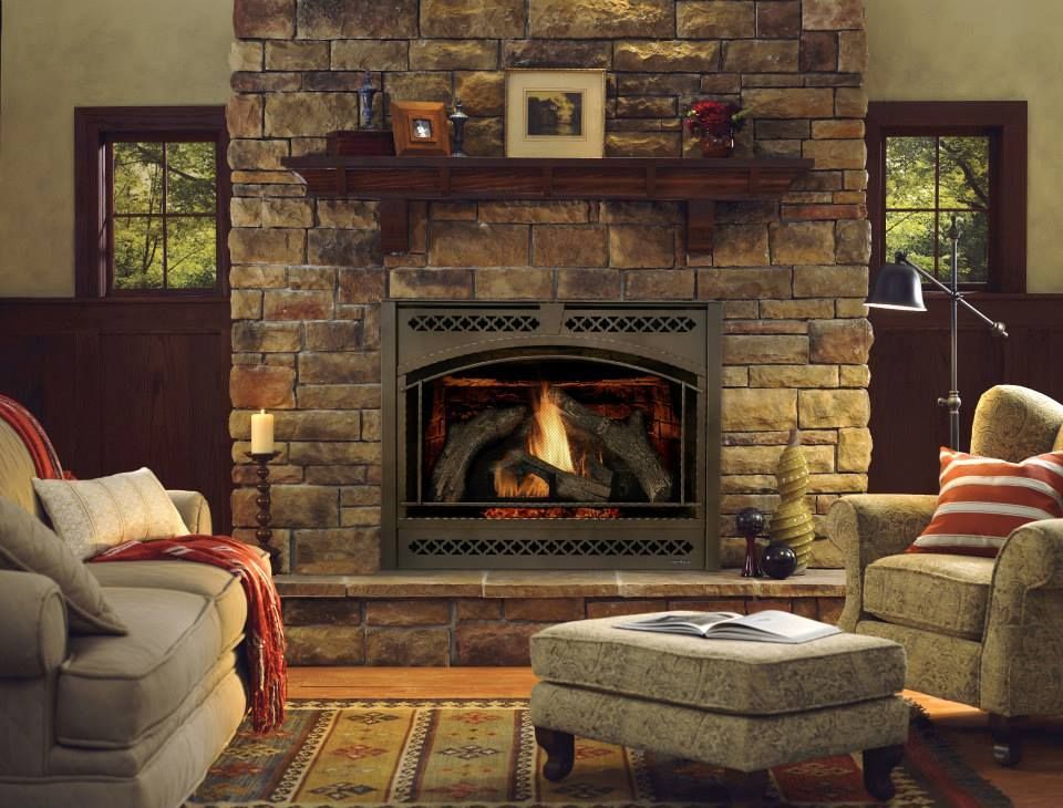 Cozy living room with stone fireplace, lit gas fire, couches, and windows.