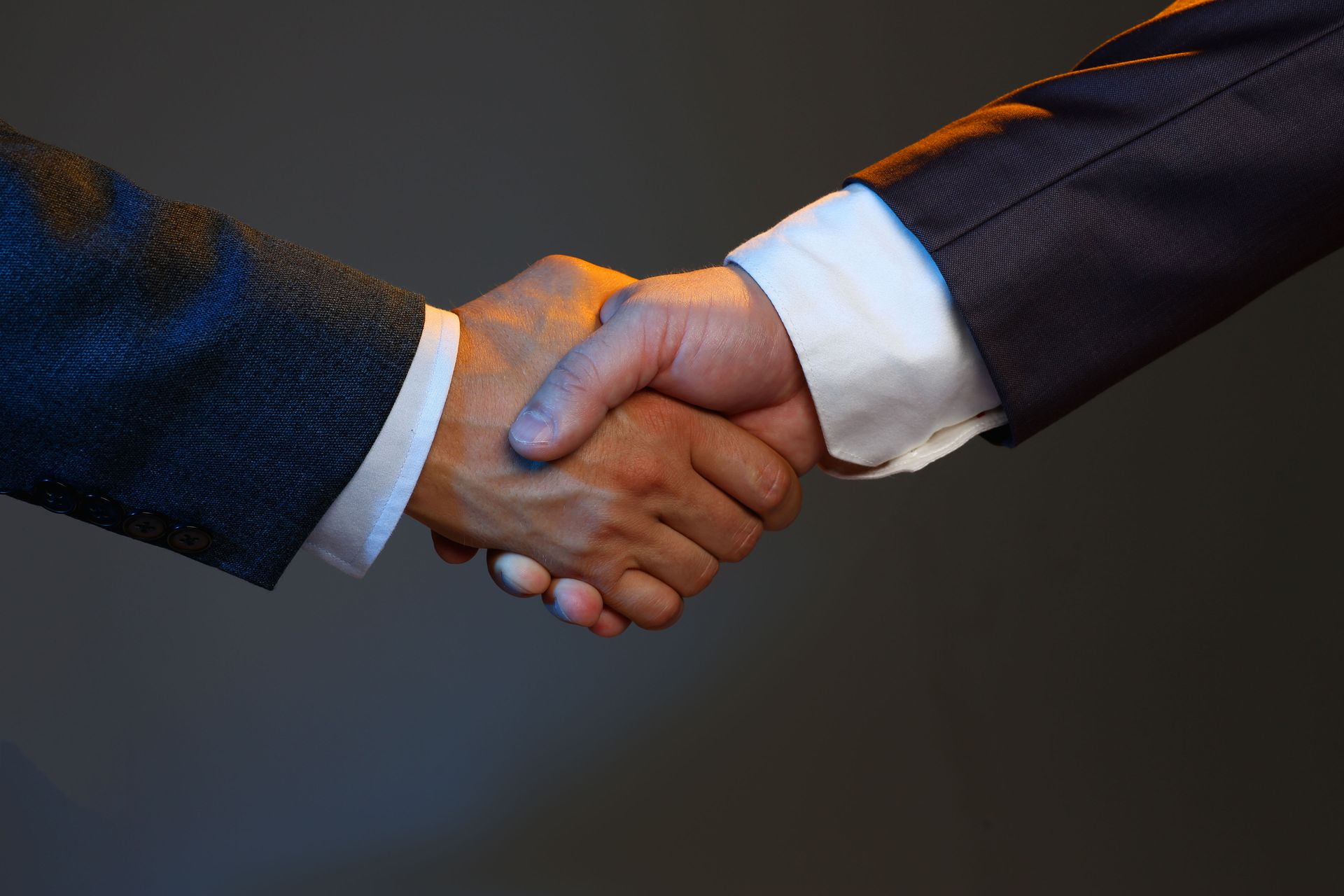 A man in a suit and a man in a white shirt are shaking hands.