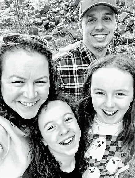 Four people smiling for a selfie outdoors, with rocks in the background.