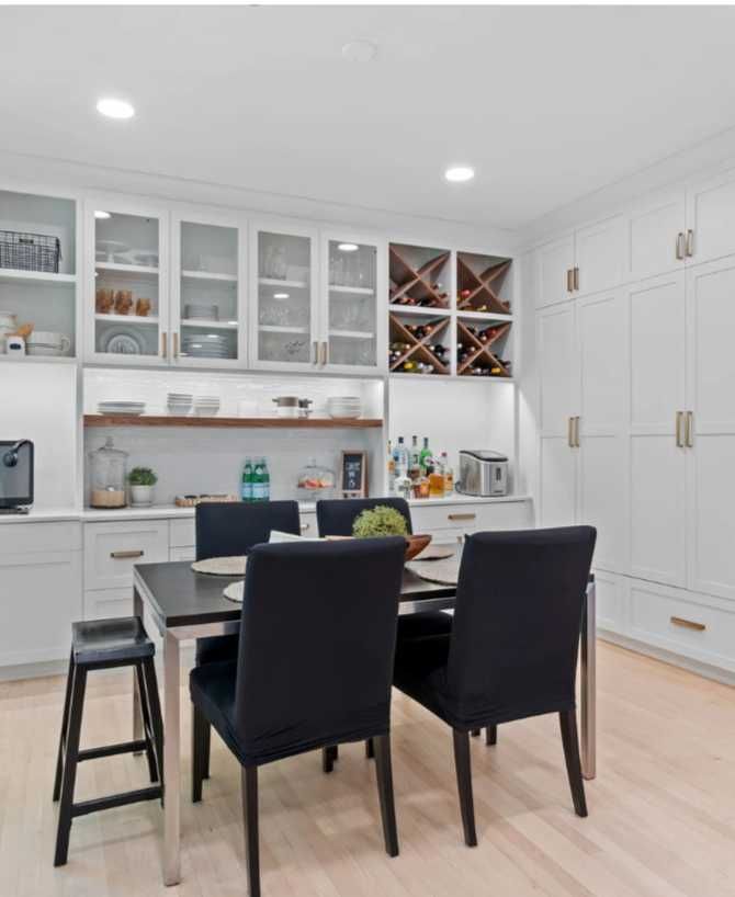 Modern white kitchen with black dining chairs and a black table in a bright, tidy interior